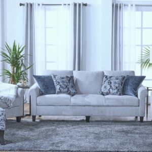 Reedy couch with four pillows on a rug in front of two tall windows