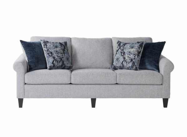 Reedy couch with three seat cushions, two solid dark pillows, and 2 patterned pillows
